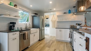 Una cocina moderna con armarios blancos, electrodomésticos de acero inoxidable y suelo de madera.