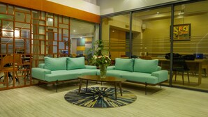 Un hall d’entrée moderne avec des canapés de couleur turquoise, une table basse et un vase décoratif.