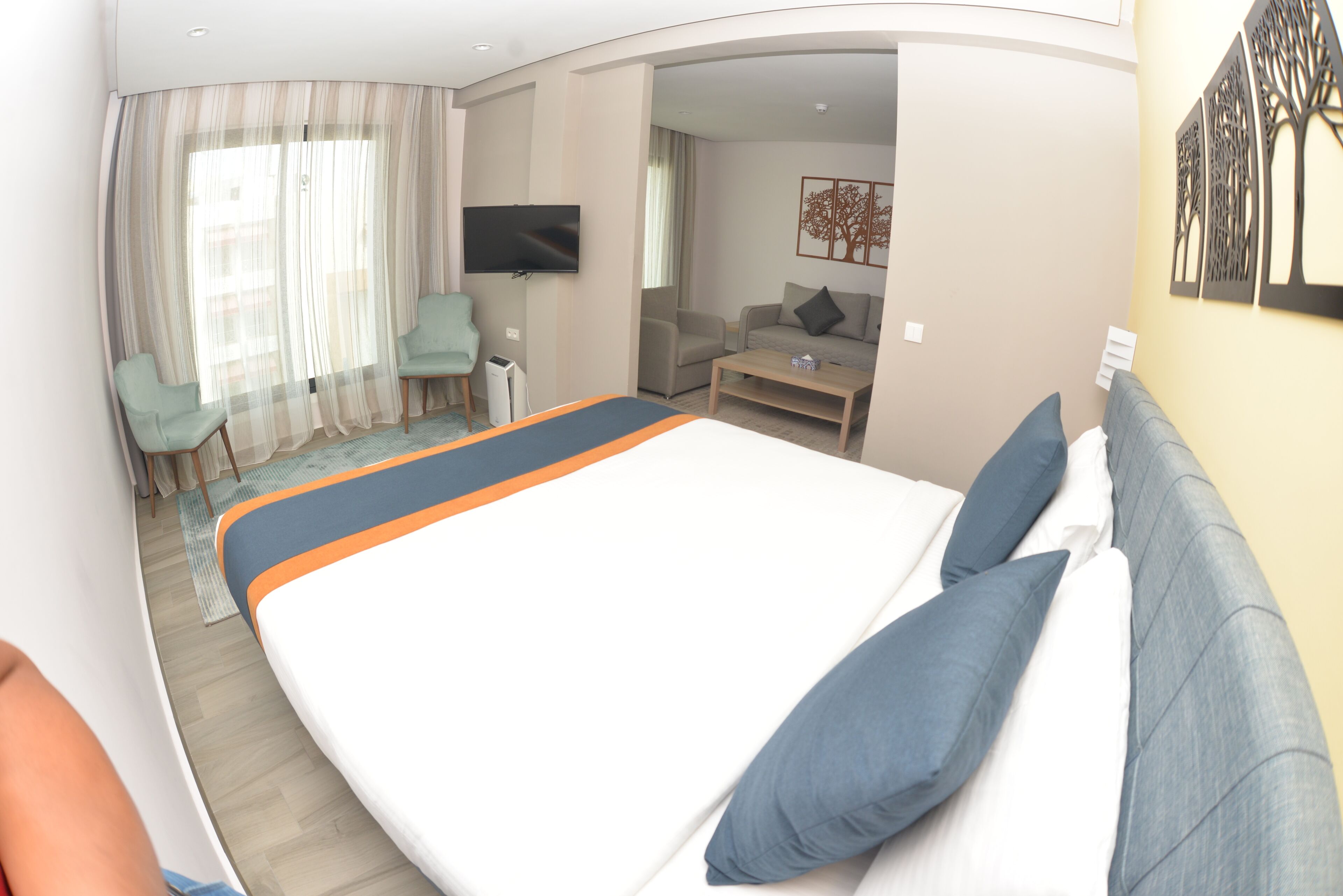 A hotel room with a large bed, a sofa, a TV, and a desk.