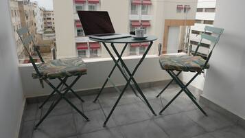 A balcony with two folding chairs, a table, and a laptop.