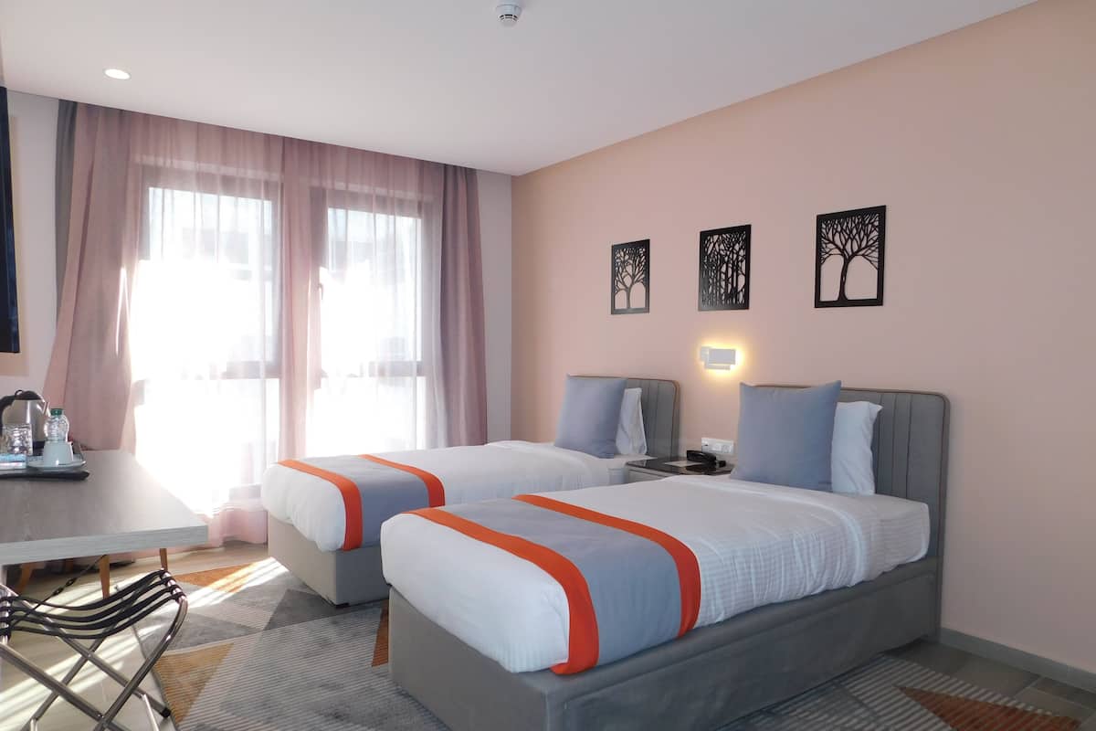Une chambre d’hôtel avec deux lits, un bureau et une chaise.