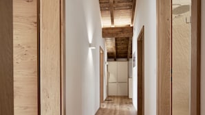 Un pasillo con pisos de madera y vigas en el techo, que conduce a una habitación con una puerta.