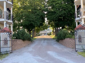 A gated driveway leading to a building with a symmetrical facade, columns, and a central entrance. - Johannesbergs Slott (Rimbo)