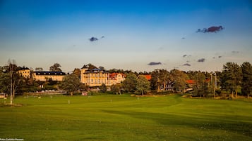 Un campo de golf con un edificio grande al fondo.