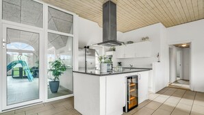 Una cocina moderna con armarios blancos, horno integrado y un ventanal con vistas a un jardín.