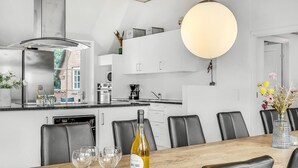 Una cocina moderna con armarios blancos, una isla grande y una zona de comedor con mesa de madera y sillas negras.