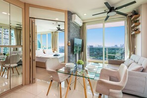 Ein modernes Wohnzimmer mit einem Glastisch, zwei Sesseln, einem Sofa und einem Deckenventilator.