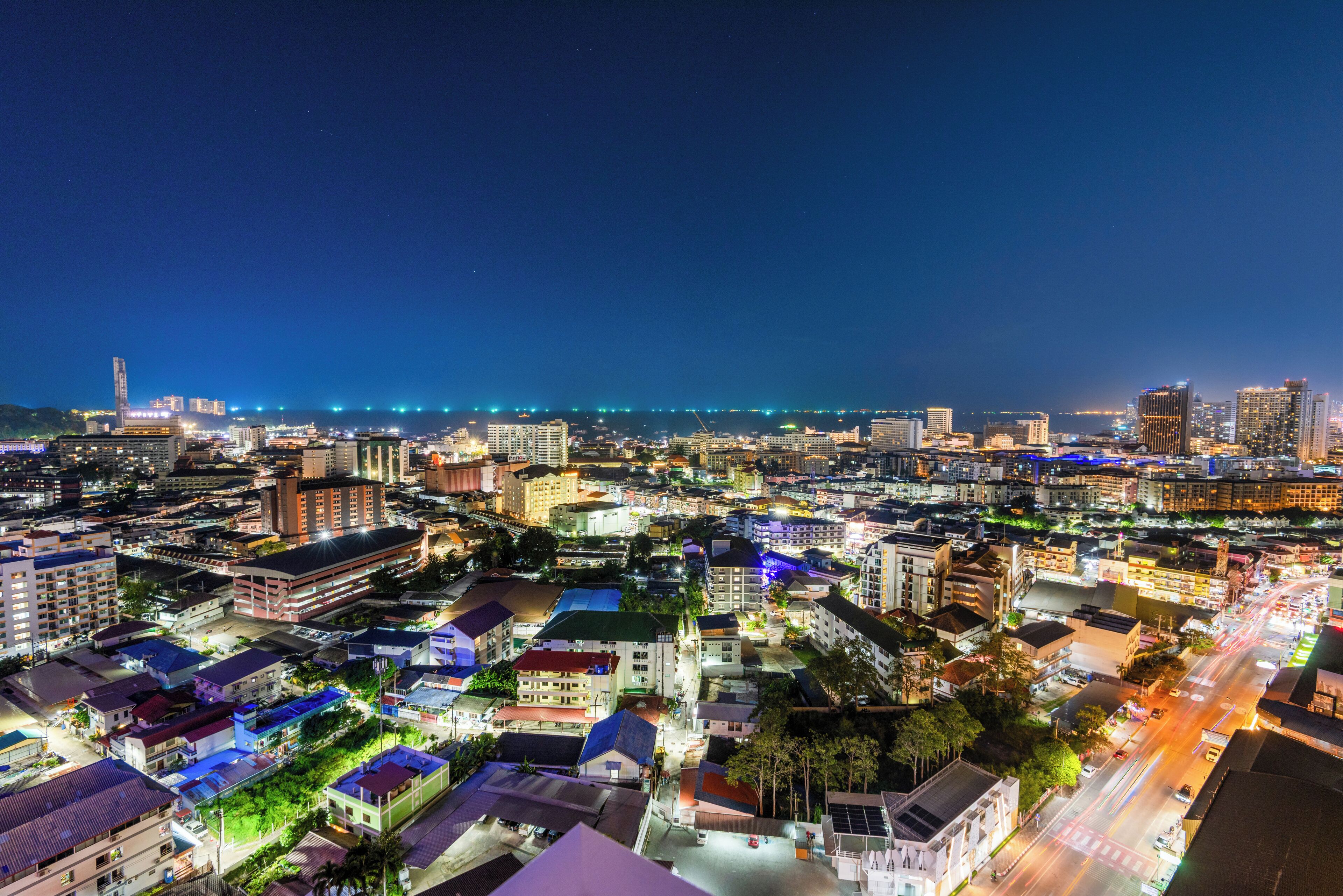 A nighttime cityscape with illuminated buildings and a view of the coastline.