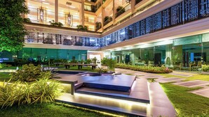 A multi-level outdoor courtyard with a pool, seating areas, and greenery. - Panoramic Sea, City And Mountain Views by City Garden Tower (Pattaya)