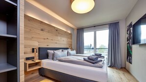 Une chambre d’hôtel moderne dotée d’un grand lit, d’une armoire intégrée et offrant une vue sur la ville.