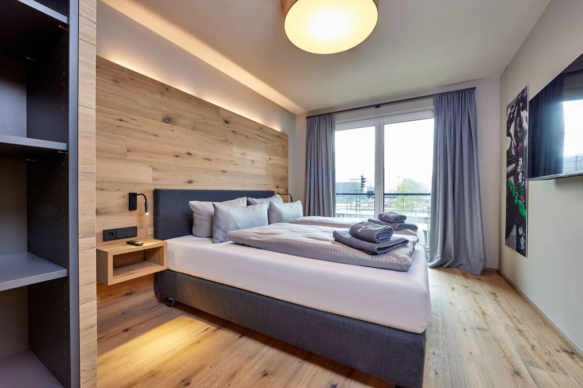 Ein modernes Hotelzimmer mit einem großen Bett, eingebautem Kleiderschrank und Blick auf die Stadt.