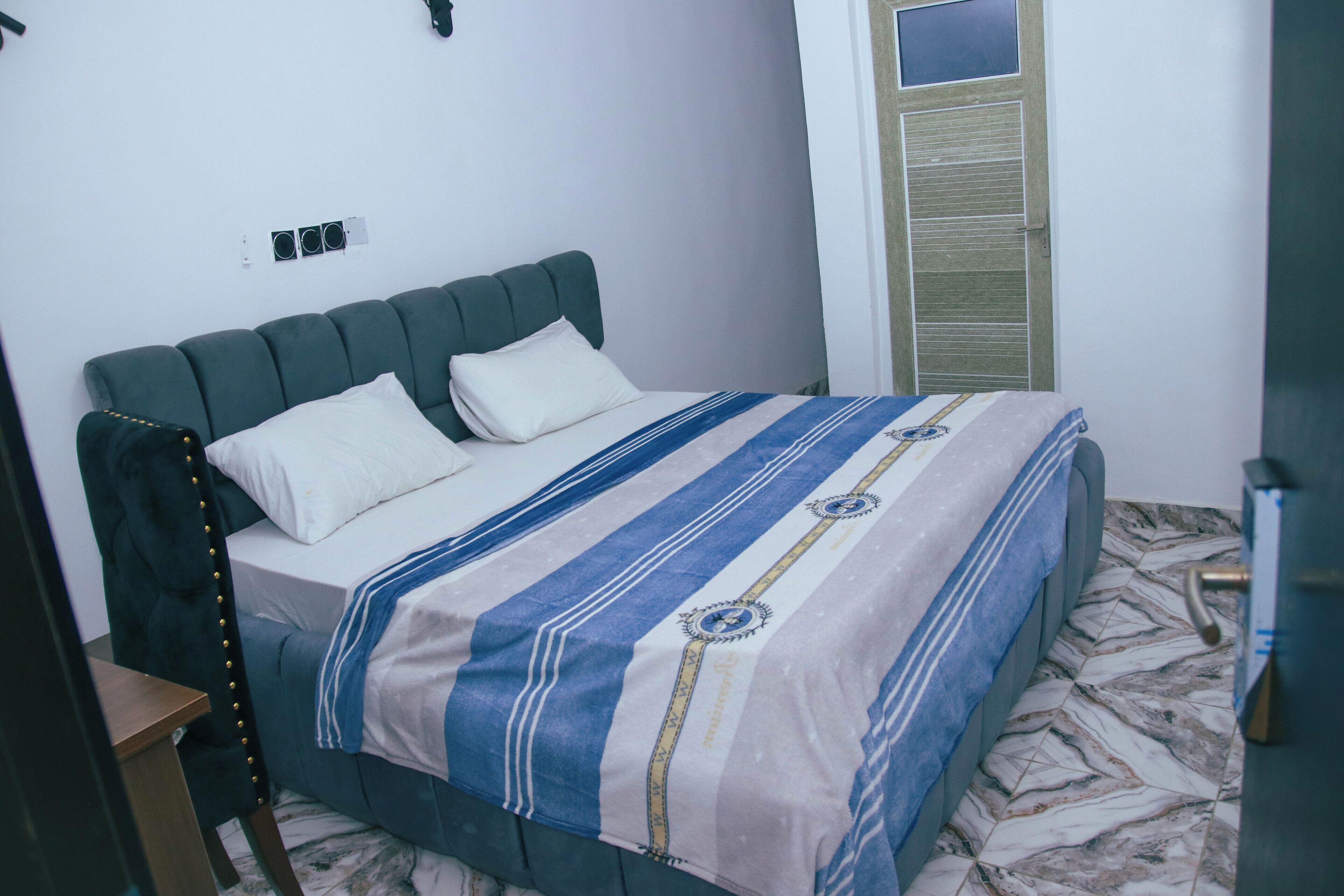 A bedroom with a bed, a nightstand, a wardrobe, and a door.
