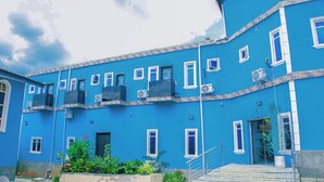A blue building with multiple windows and air conditioning units. - Xela Hotels and Resorts (Ife)