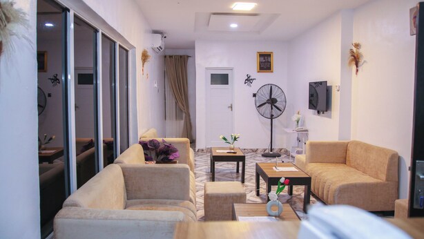 A modern living room with a sofa, coffee table, and a fan. - Xela Hotels and Resorts (Ife)