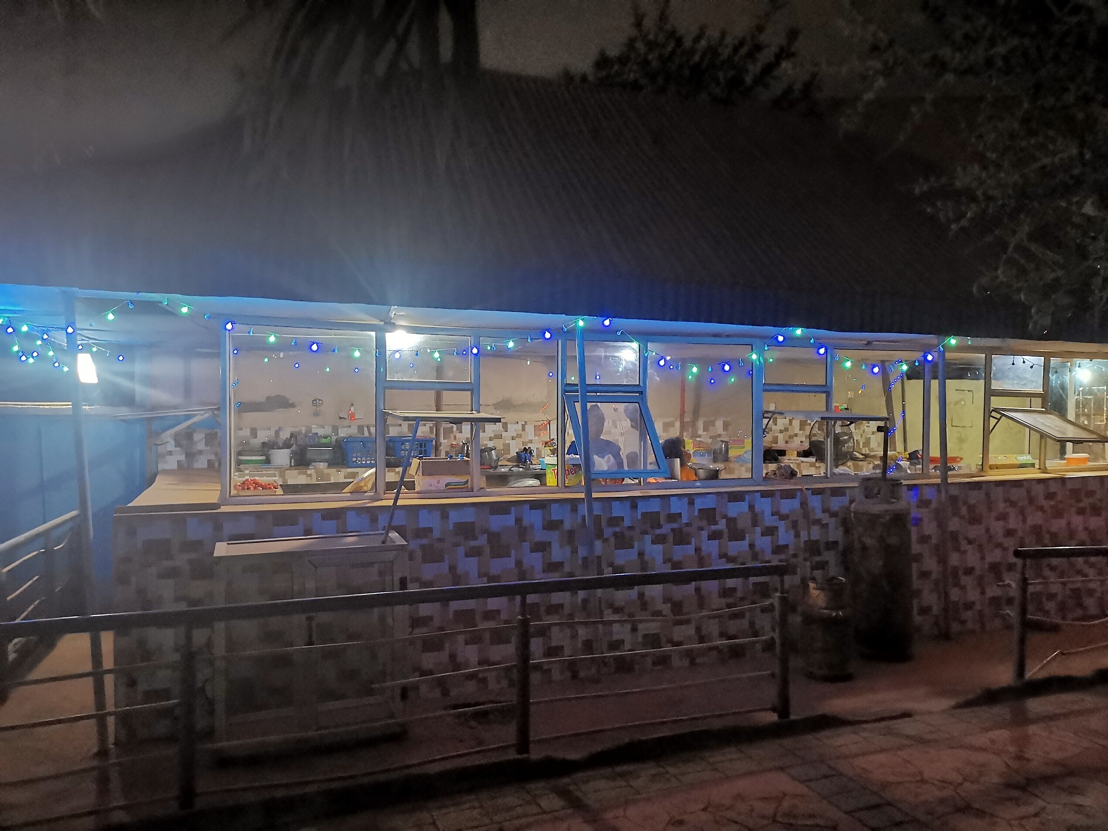 A food stall with a tiled exterior and glass windows, decorated with string lights.