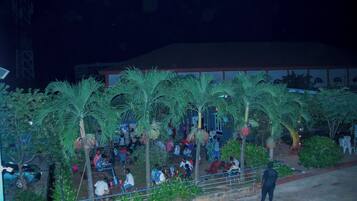 Un espacio al aire libre para reuniones con palmeras y una zona de estar cubierta.