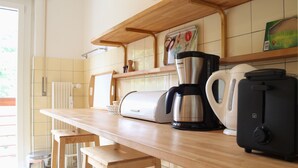 A kitchen with a wooden countertop, a coffee maker, a toaster, and a kettle. - Central & Cozy - Rainbow A (Lens)