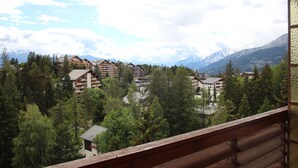 A mountain lodge with multiple buildings surrounded by dense forest and snow-capped mountains in the background. - Central & Cozy - Rainbow A (Lens)