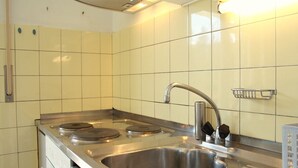 A kitchen with a stainless steel sink, a stove, and a faucet. - Cozy & Central - Palma B (Lens)