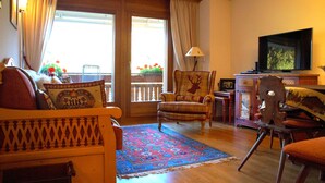 A cozy living room with a sofa, armchair, and a television on a stand. - Charming & Intimate - Estoril (Crans-Montana)