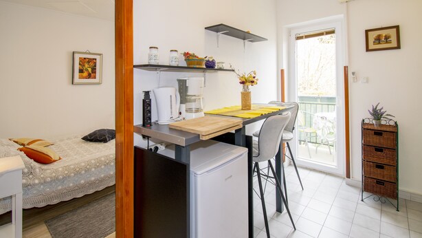 A compact kitchen with a refrigerator, a coffee maker, and a small dining area with a chair and table. - Vacation apartment GABI, Near the beach (Premantura)
