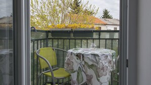 A balcony with a table and chair, a view of trees and a building in the background. - Vacation apartment GABI, Near the beach (Premantura)