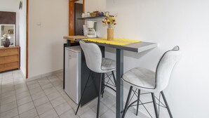 A compact kitchen with a refrigerator, a coffee maker, and a small dining table with two chairs. - Vacation apartment GABI, Near the beach (Premantura)