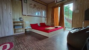 A bedroom with a wooden bed, red bedding, a small bedside table, a shelf with items, and a window with curtains. - I-Camp Resort (Wai)