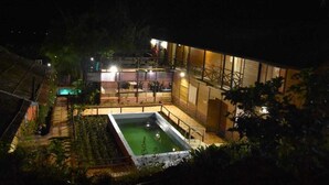 A well-lit outdoor area with a swimming pool, a covered seating area, and a building with large windows. - I-Camp Resort (Wai)