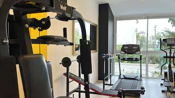 A gym with various exercise equipment, including a bench press, a squat rack, and a treadmill.
