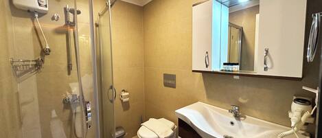 A modern bathroom with a glass shower enclosure, a white sink with a vanity, and a large mirror above the sink.