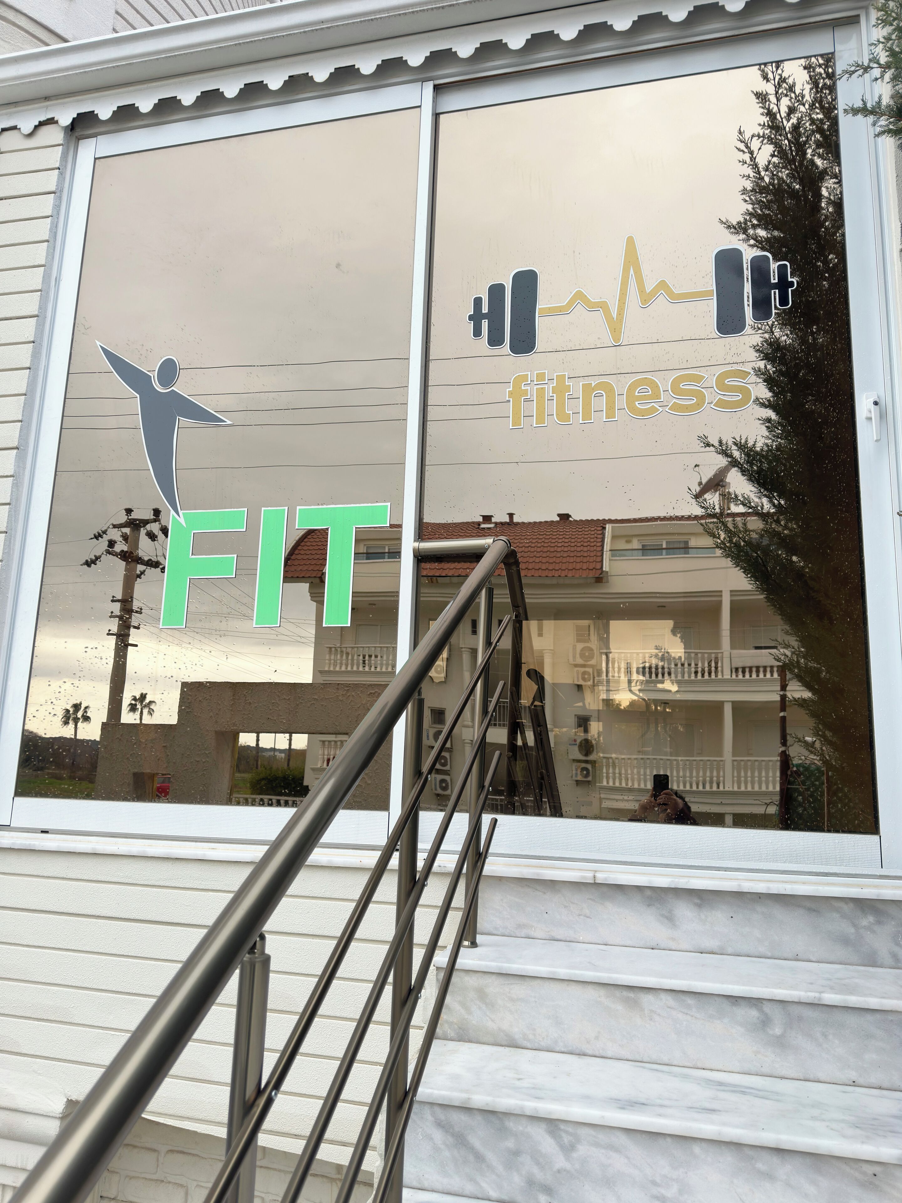 A fitness center with a large window displaying a logo and the word "FITNESS".