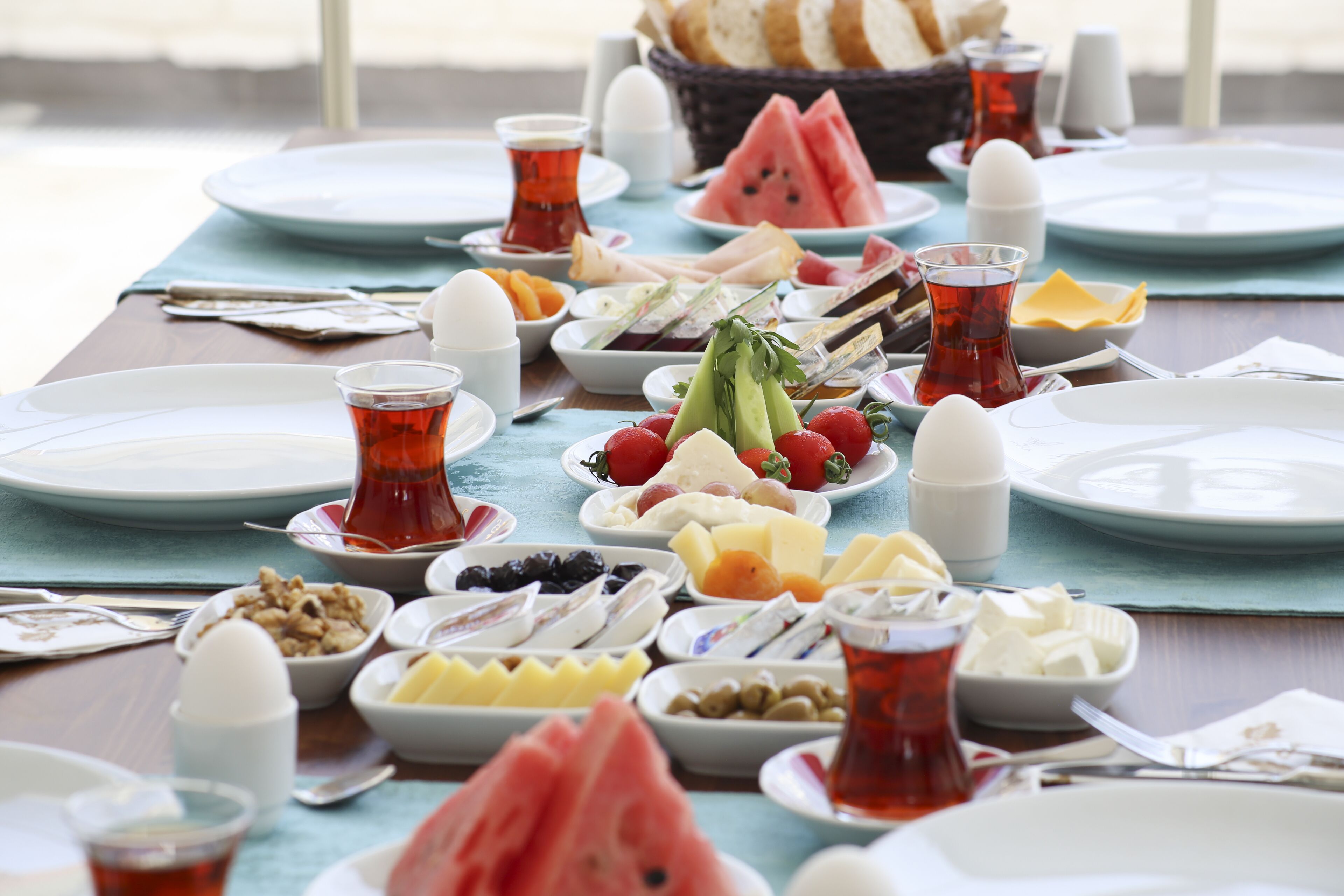 Una mesa dispuesta con diversos productos para el desayuno, como frutas, quesos y pan, con vista al mar.