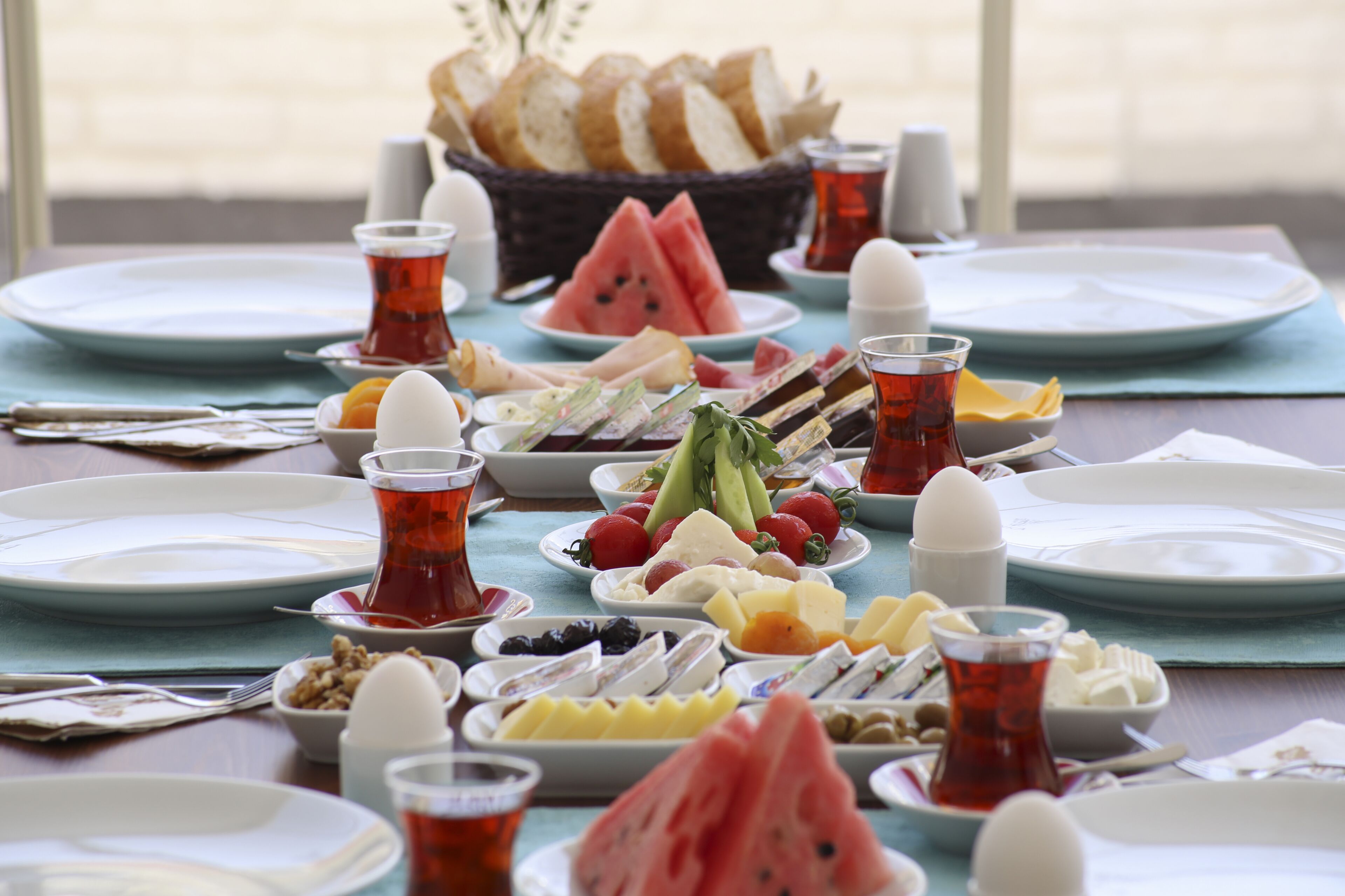Una mesa dispuesta con diversos platos, incluyendo frutas, quesos y pan, con vista al exterior.