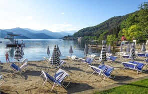 A beach with sun loungers and umbrellas, a lifeguard tower, and mountains in the background. - Nice home in Gozzano with WiFi (Gozzano)