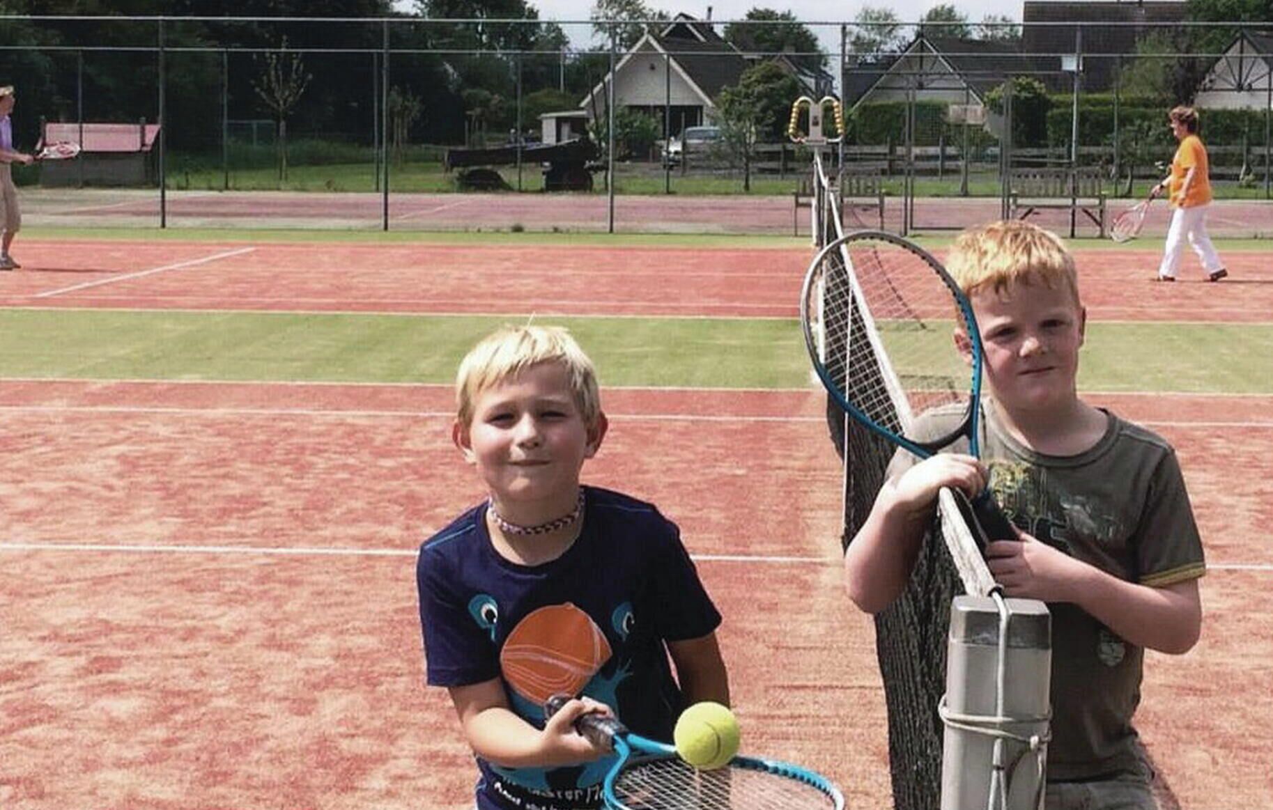 A tennis court with two players holding rackets and a tennis ball.