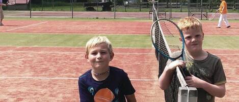 A tennis court with two players holding rackets and a tennis ball.