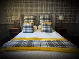 A neatly made bed with a plaid bedspread and pillows, flanked by two bedside tables with lamps.