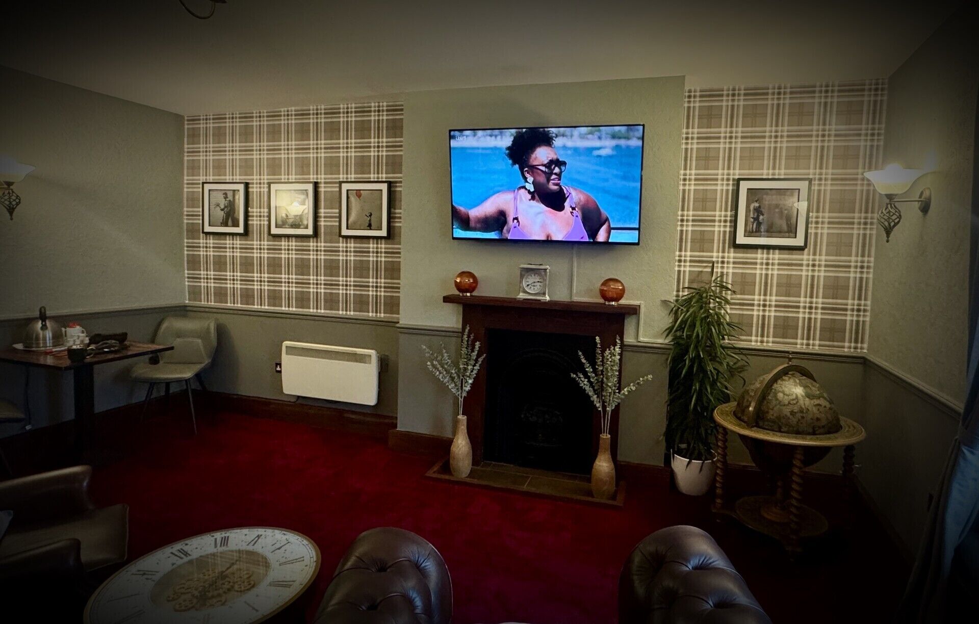 Una sala de estar con chimenea, televisor y cuadros en la pared.