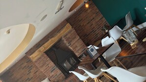 A restaurant interior with brick walls, wooden flooring, and white chairs. - Ivy By The Sea (Scarborough)
