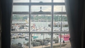 A view through a window with a grid pattern, overlooking a marina with boats and a distant building. - Ivy By The Sea (Scarborough)