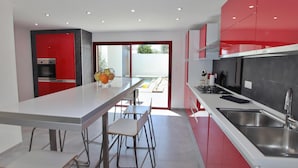 Eine moderne Küche mit roten Schränken, einer Edelstahlspüle und einem eingebauten Backofen.