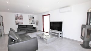 Ein modernes Wohnzimmer mit grauem Sofa, Couchtisch, Flachbildfernseher und Kamin.