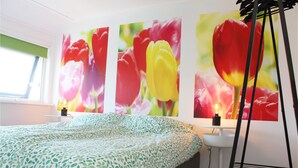 A bedroom with a bed, a bedside table, a lamp, and a wall with three large floral paintings. - Amazing home in Grou with WiFi (Grou)