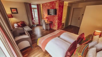 A hotel room with a bed, a desk, a chair, a TV, and a bathroom.