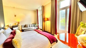 Ein Hotelzimmer mit Bett, Sofa, Tisch und Blick ins Freie.