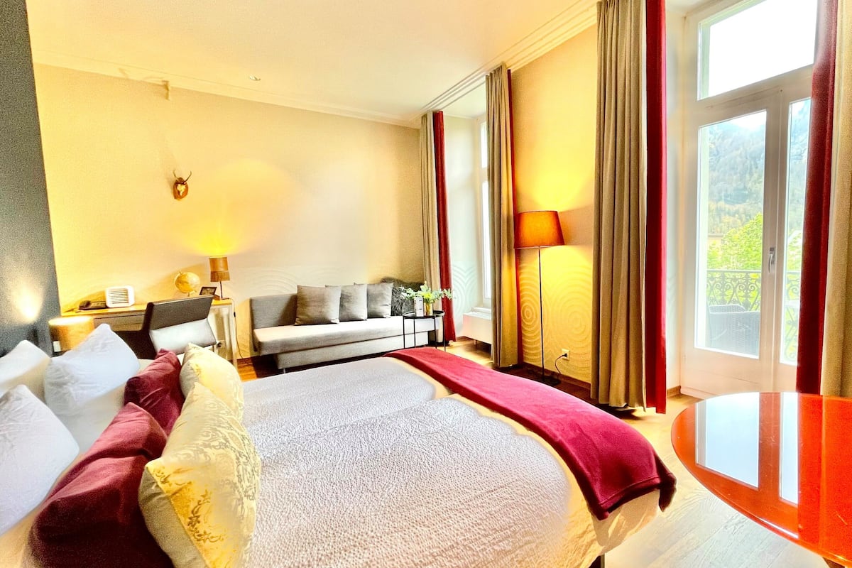 Une chambre d’hôtel avec un lit, un canapé, une table et une vue sur l’extérieur.