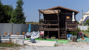 A wooden structure with a covered porch, a small staircase, and a blue umbrella.