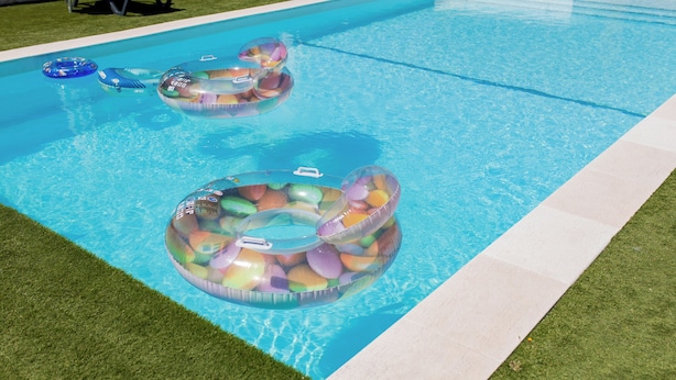 A swimming pool with two inflatable rings filled with colorful objects.