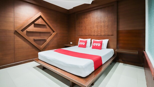 A hotel room with a large bed, wooden paneling, and a built-in shelf. - OYO 1172 Goodnight Resort (Phuket)